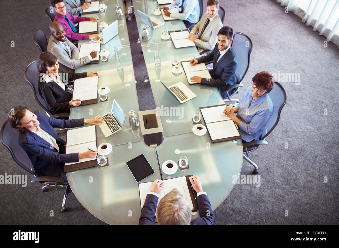Group of businesspeople sitting at conference table looking at chairman Stock Photo