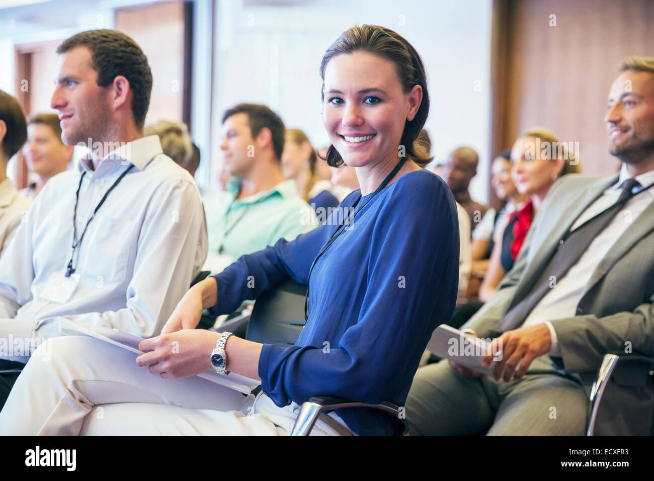 Portrait of smiling young woman sitting in audience in conference room Stock Photo