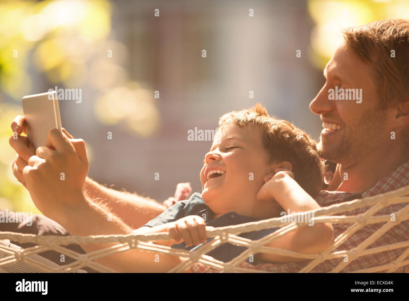 Father and son using digital tablet in hammock Stock Photo