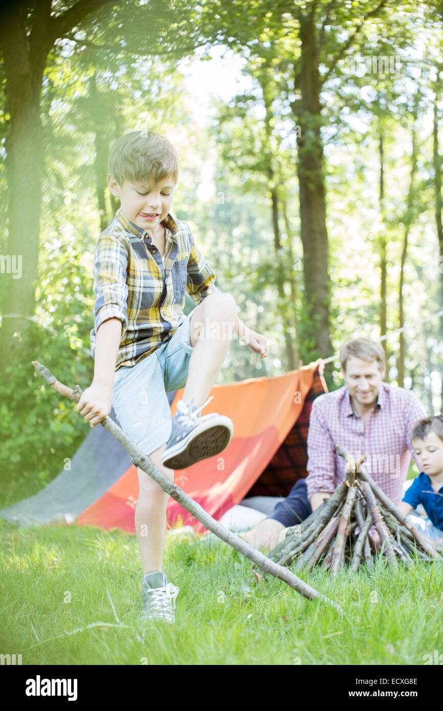 Boy breaking stick for campfire with father and brother Stock Photo