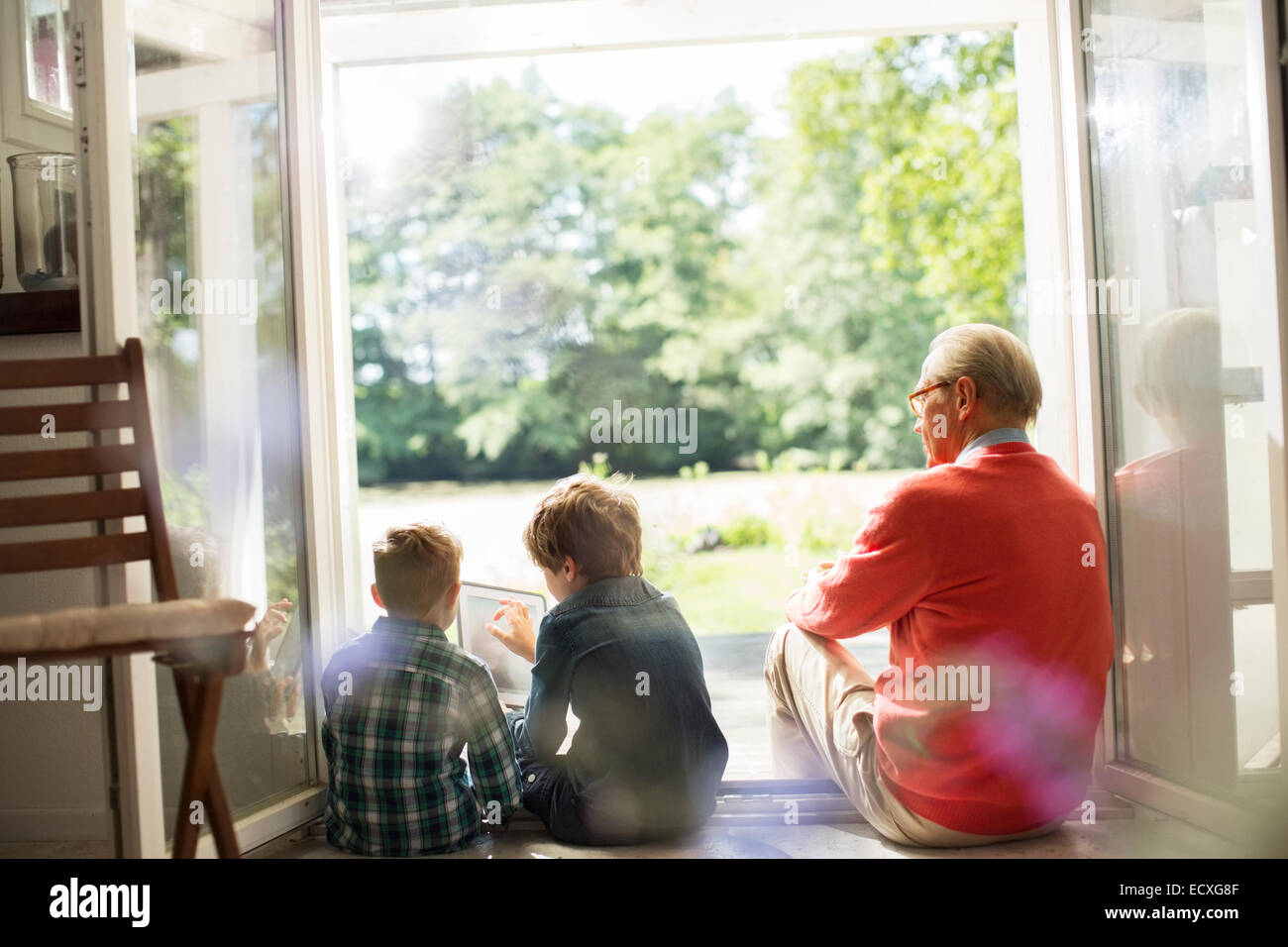 Grandfather and grandsons relaxing in doorway Stock Photo