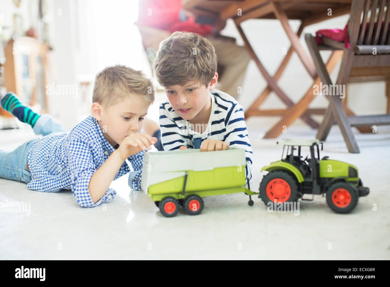 Brothers playing with toy tractor on floor Stock Photo