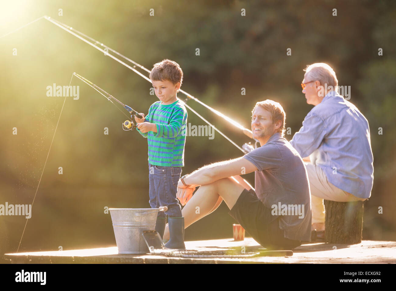 Boy, father and grandfather fishing on wooden dock Stock Photo