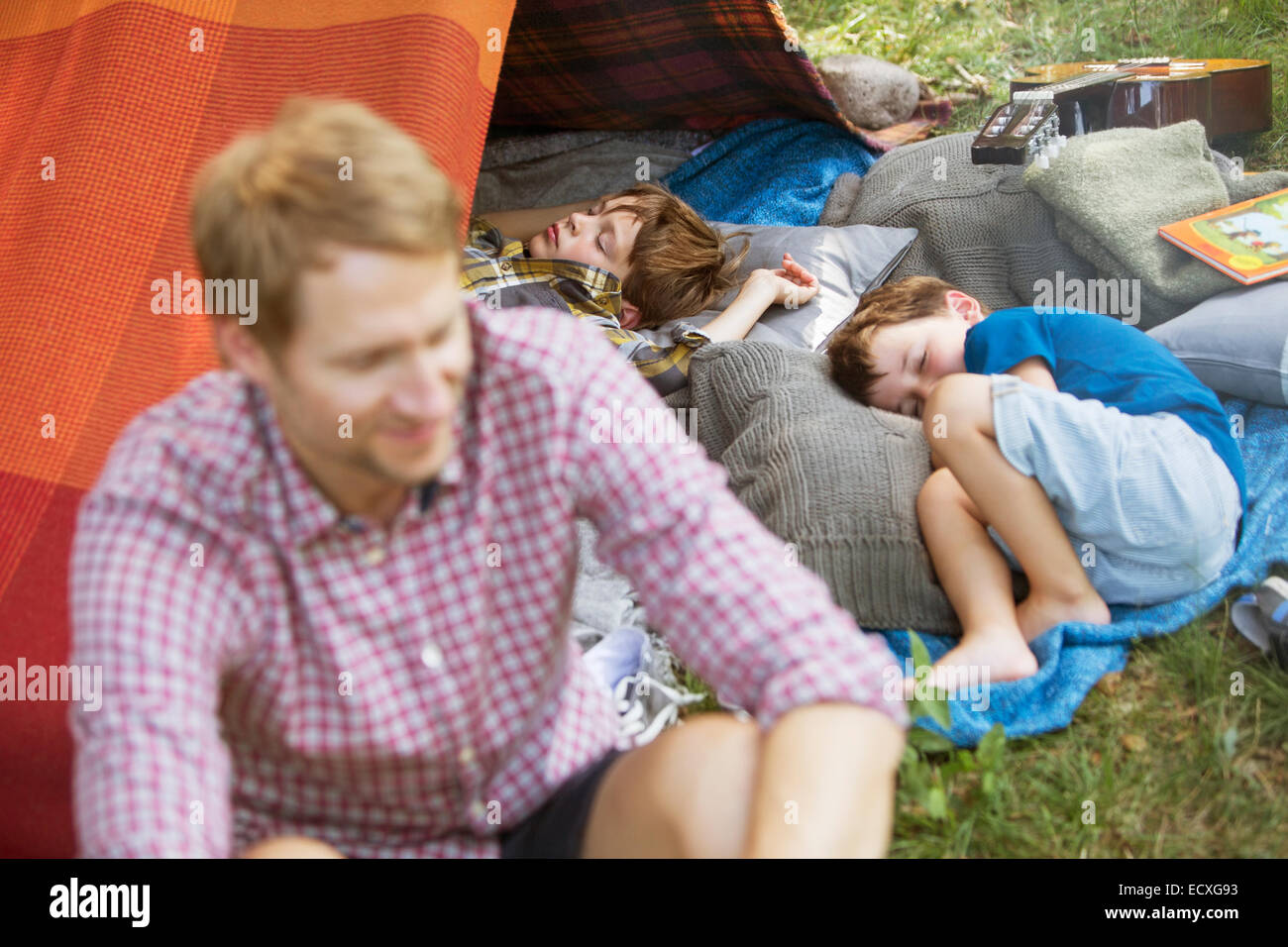 Father sitting with sleeping sons at camping tent Stock Photo