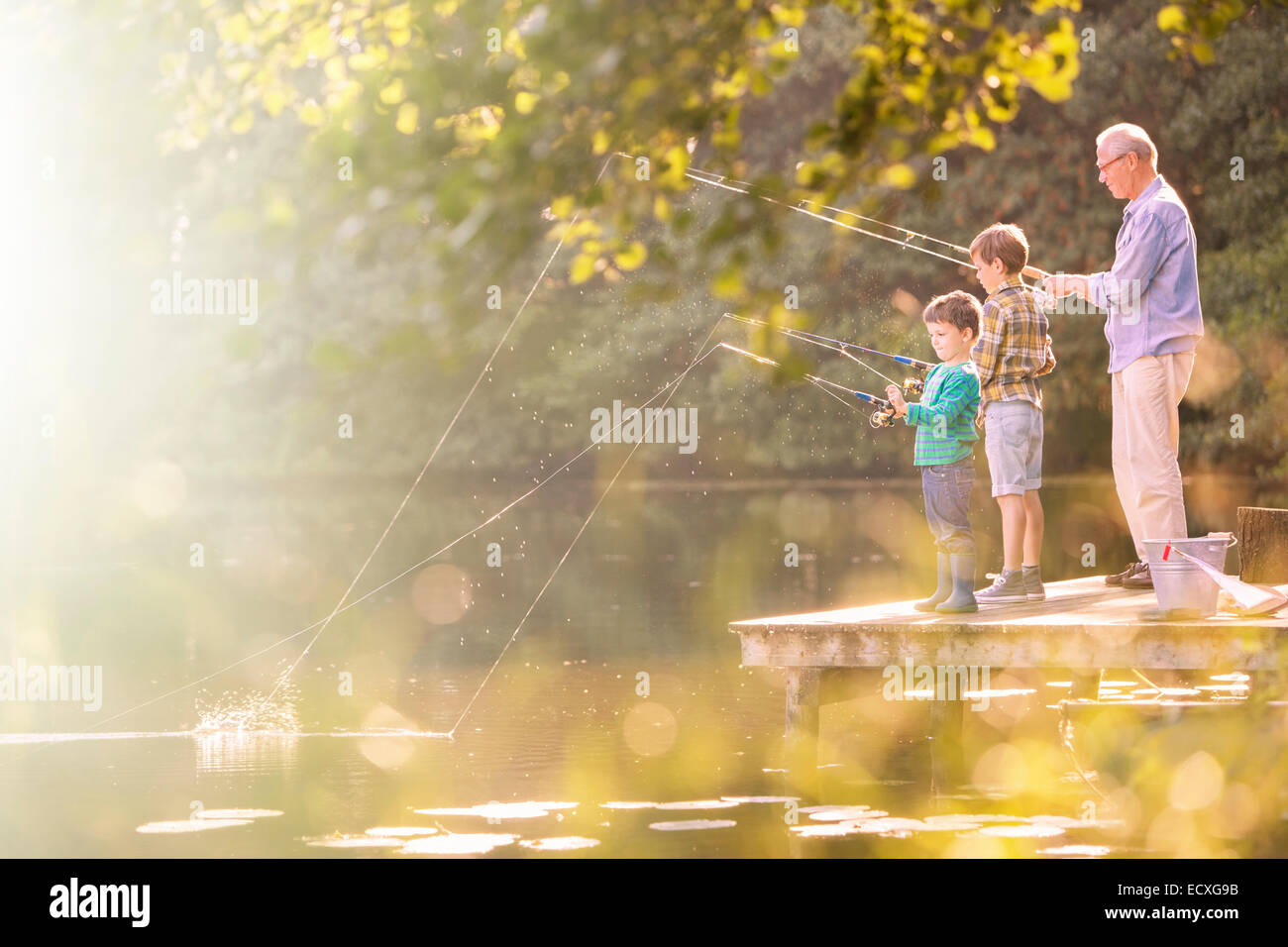 Grandfather and grandsons fishing at lake Stock Photo
