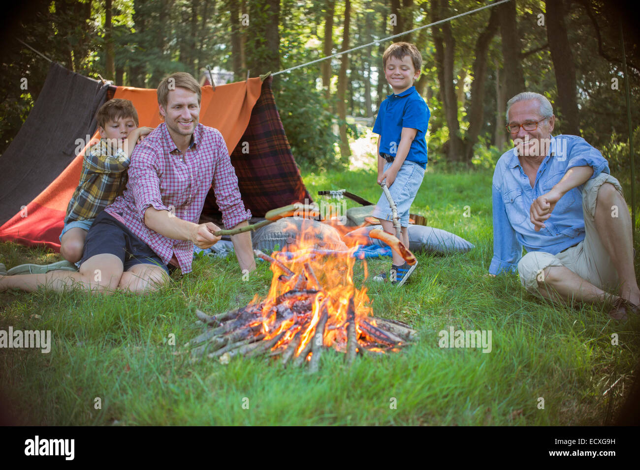 Boy, father and grandfather relaxing near campfire Stock Photo