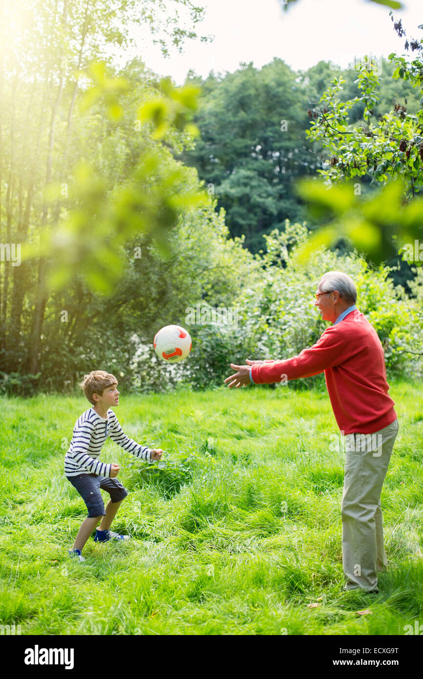 Grandfather and grandson playing soccer in grass Stock Photo