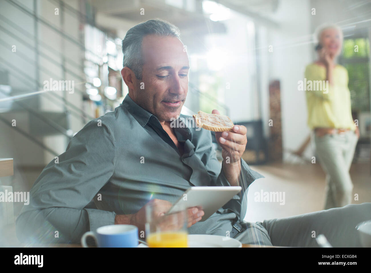 Older man using digital tablet at breakfast table Stock Photo