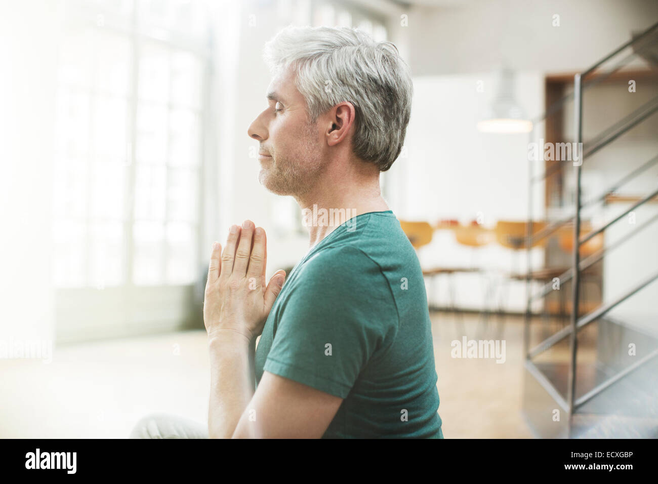 Older man meditating indoors Stock Photo