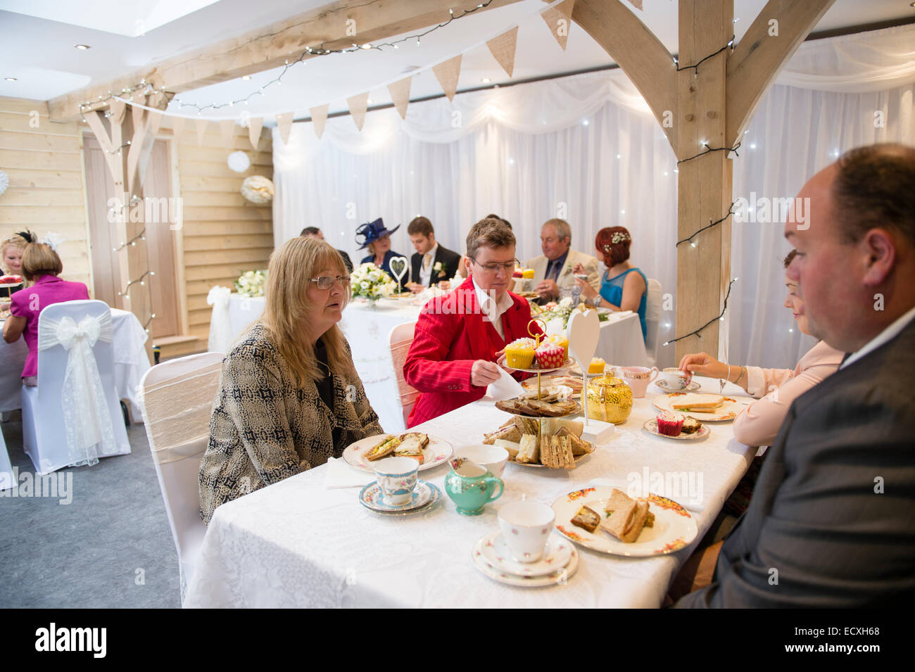 Getting married / Wedding day UK: people enjoying themselves eating sandwiches and drinking tea at an alcohol-free wedding reception celebration party after the wedding service Stock Photo