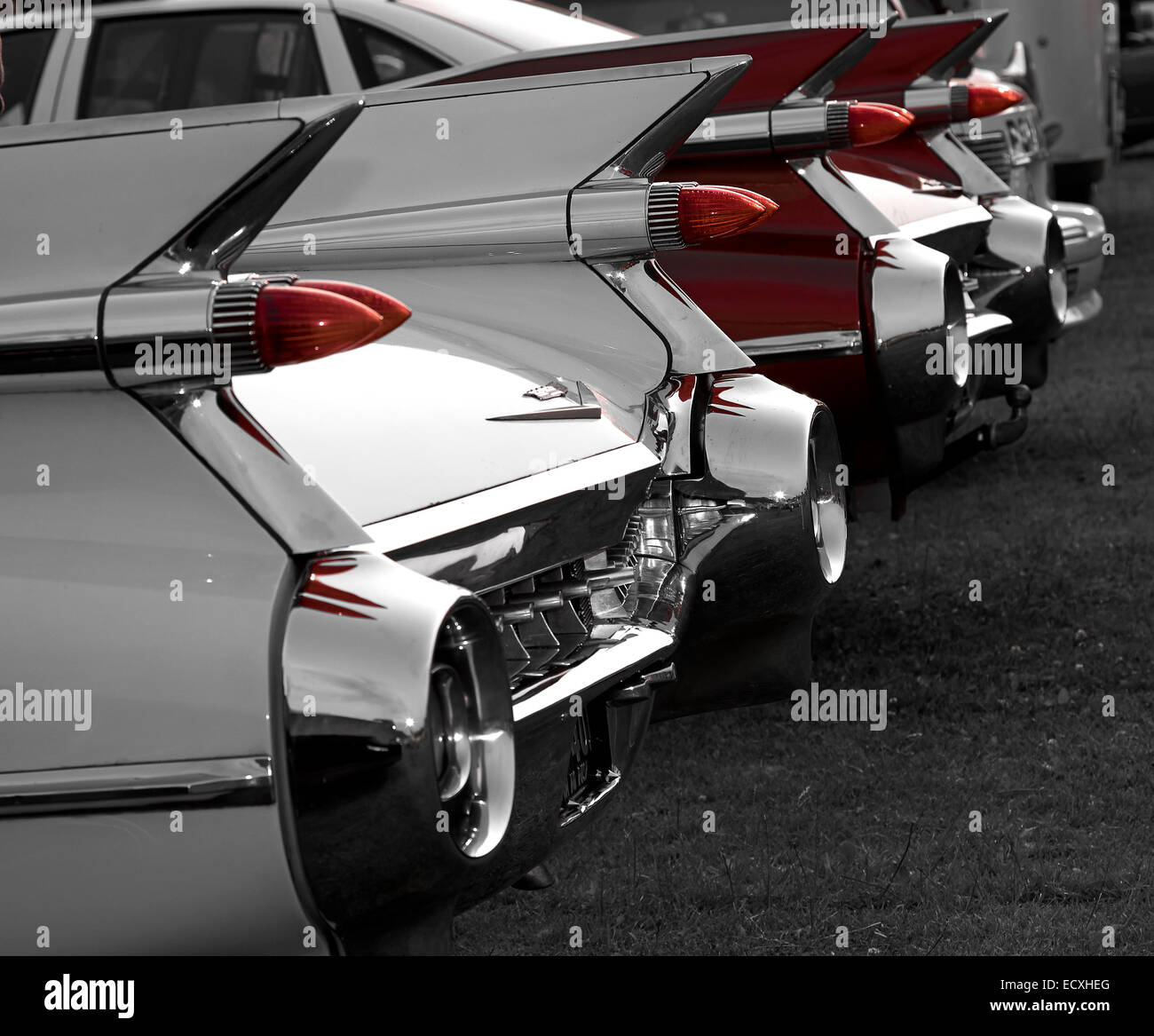 Fins and rear bumper on two vintage Cadillac Eldorado. Monochrome except for red of one car and tail-lights. Stock Photo