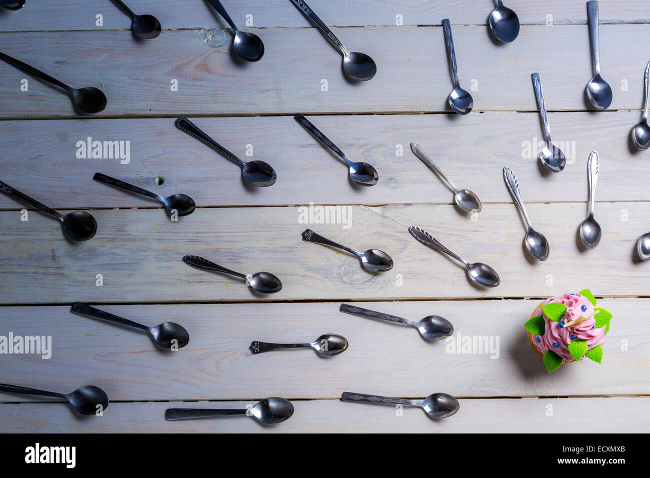 Flock of teaspoons and one muffin Stock Photo