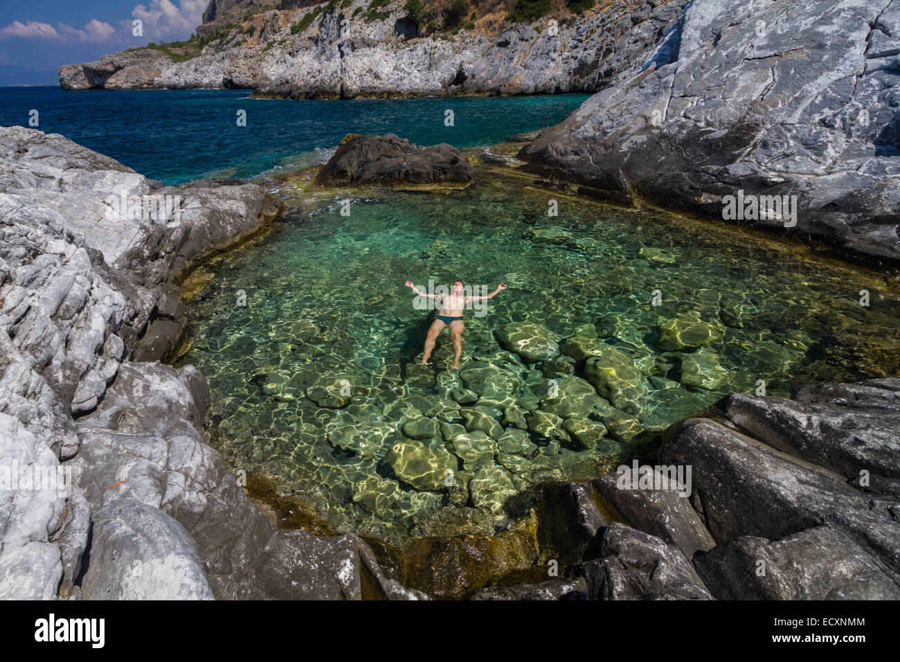 A man relaxing on the water of a natural pool with sea water. Trachila village, Messenia, Greece Stock Photo