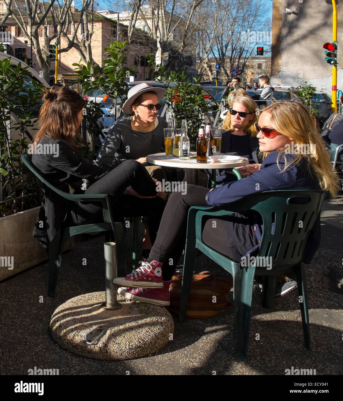 group young people sitting outside bar drinks Stock Photo