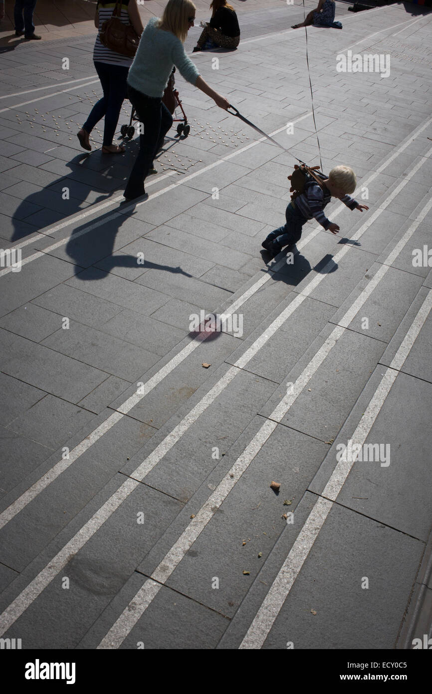 A mother controls pulling away child with reins on Southbank steps. Stock Photo