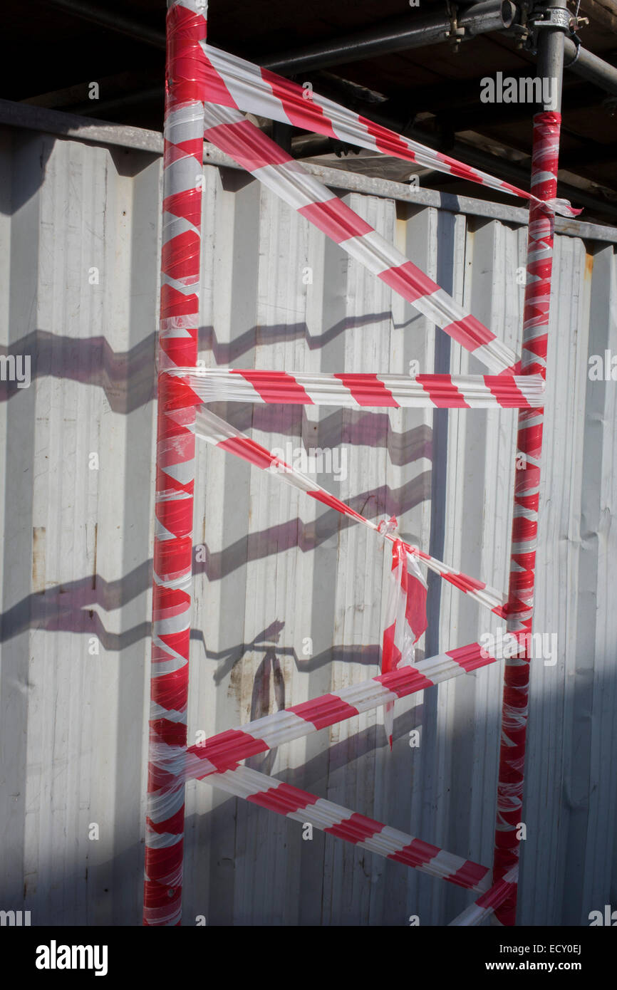Red and white striped tape covers scaffolding on a south London construction site. Stock Photo
