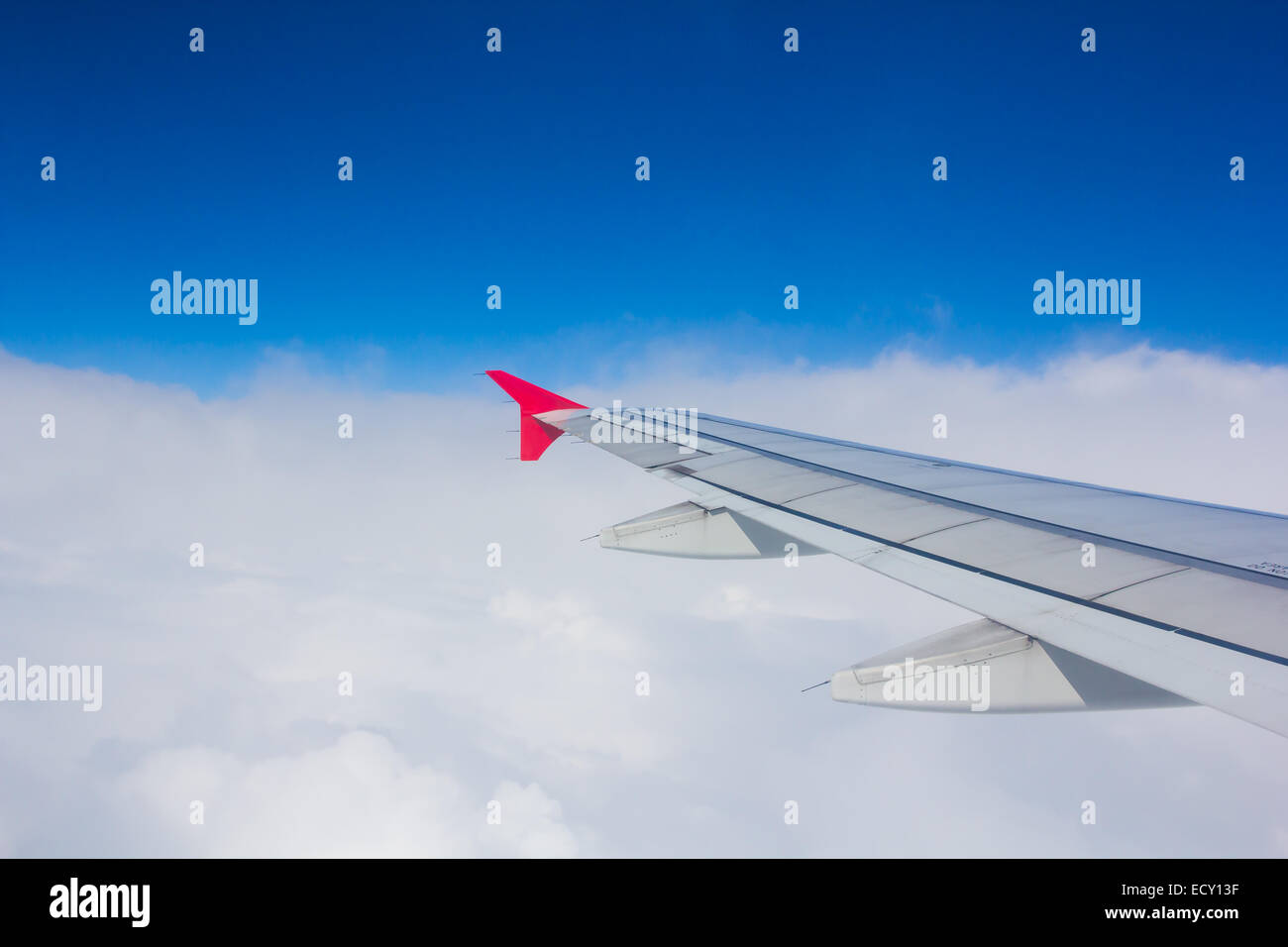 Wing airplane flying above clouds looking at the sky from the window, using air transport to travel. Stock Photo