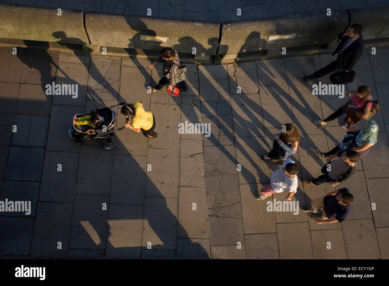 The long shadows of strangers as they walk along London's Southbank. Stock Photo