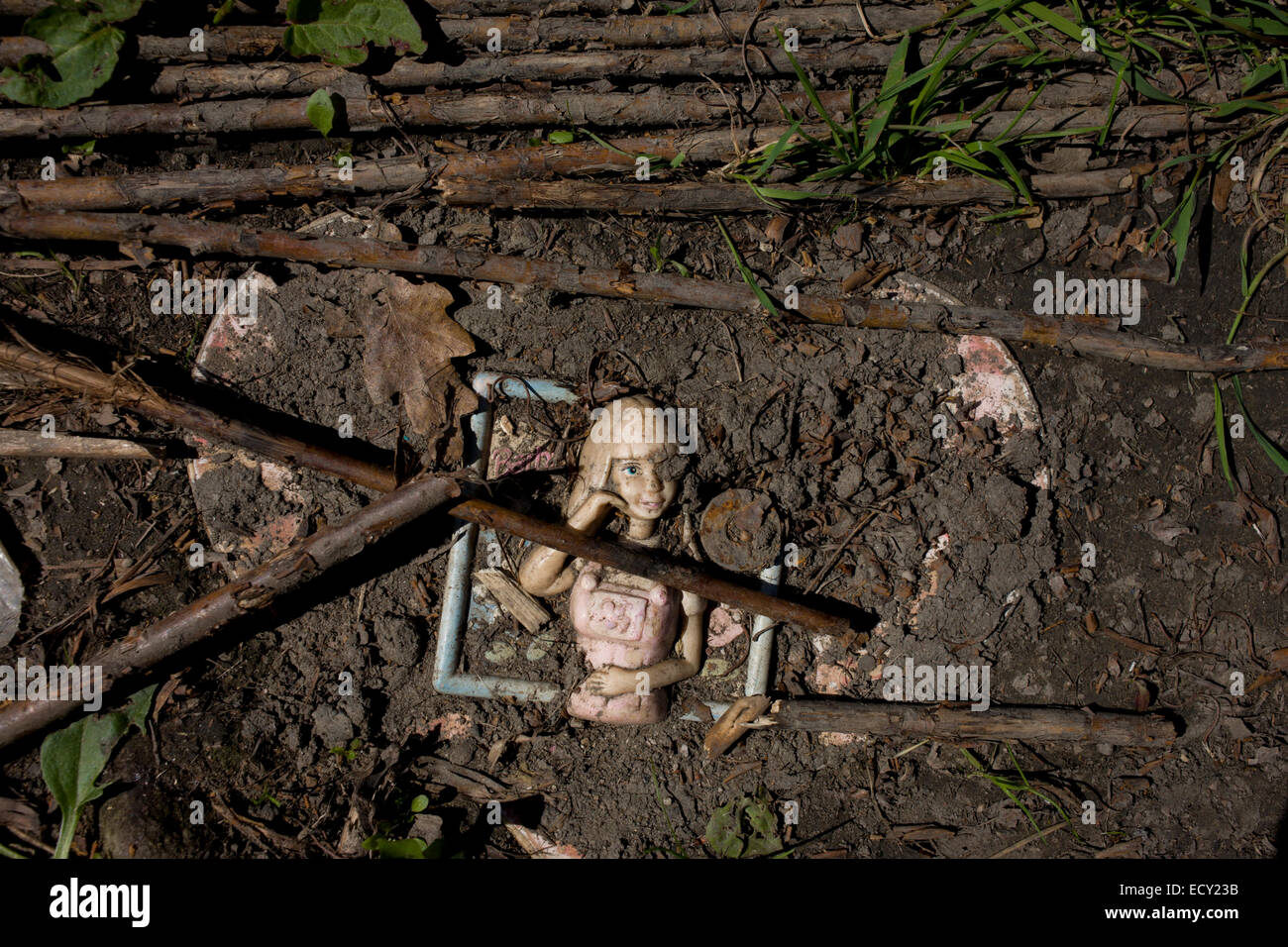 Doll trodden into soil in risk averse playground called The Land on Plas Madoc Estate, Ruabon, Wrexham, Wales. Stock Photo