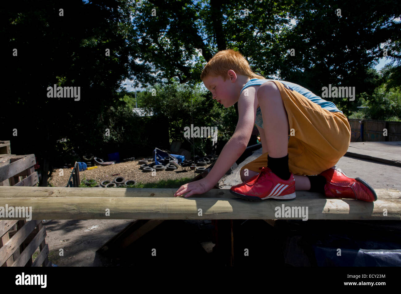 Boy plays in risk averse playground called The Land on Plas Madoc Estate, Ruabon, Wrexham, Wales. Stock Photo