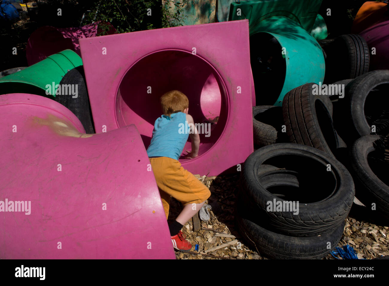 Boy climbs through tunnels in risk averse playground called The Land on Plas Madoc Estate, Ruabon, Wrexham, Wales.   From the ch Stock Photo