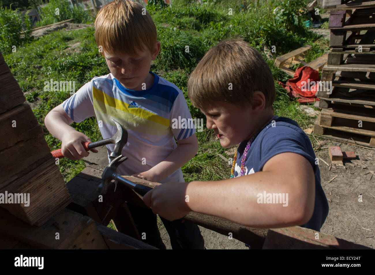 Boys use claw hammers in risk averse playground called The Land on Plas Madoc Estate, Ruabon, Wrexham, Wales. Stock Photo