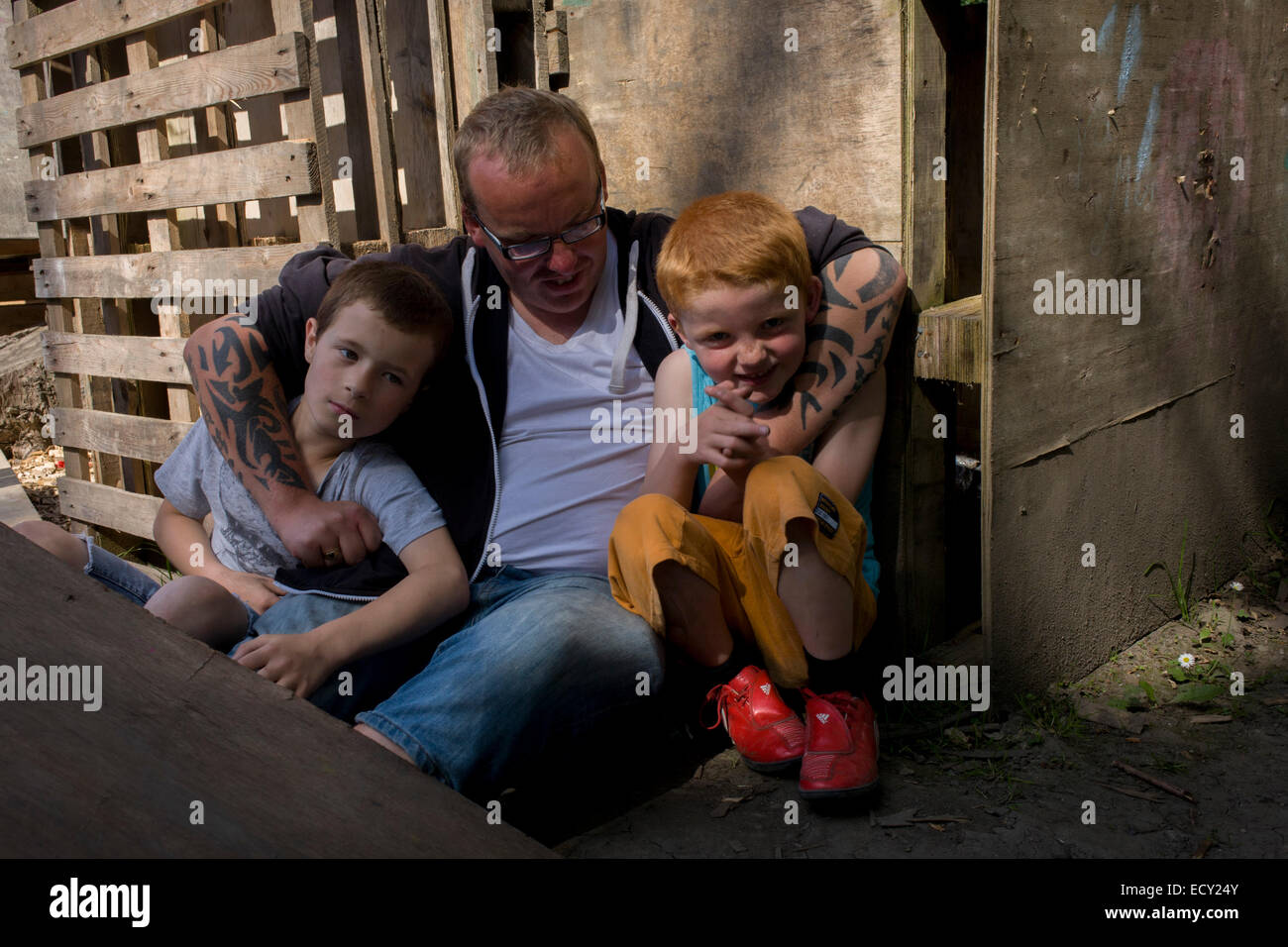 Father and boys in risk averse playground called The Land on Plas Madoc Estate, Ruabon, Wrexham, Wales. Stock Photo