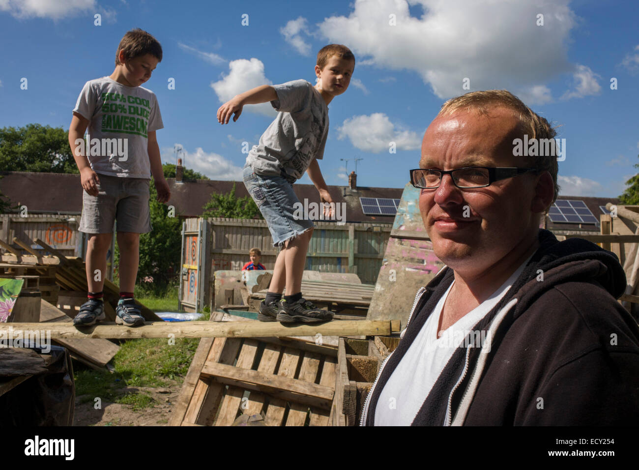 Father and boys in risk averse playground called The Land on Plas Madoc Estate, Ruabon, Wrexham, Wales. Stock Photo