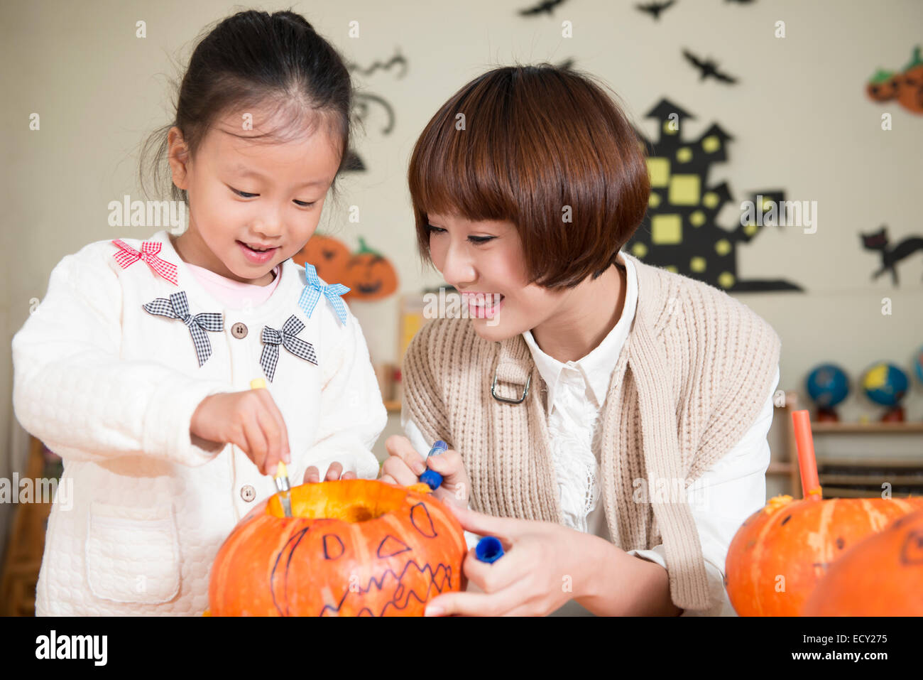 Kindergarten teacher and girl carving pumpkin Stock Photo