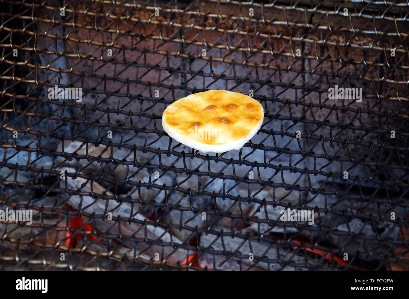 Single Japanese senbei being grilled over charcoal Stock Photo