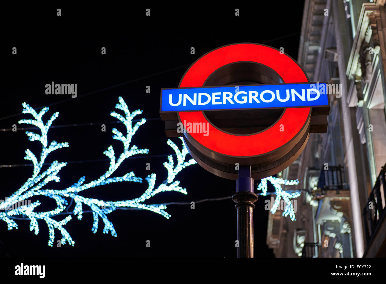 LONDON, UK - DECEMBER 20: Nighttime shot of London underground entrance sign with Christmas lights in the background. December 2 Stock Photo