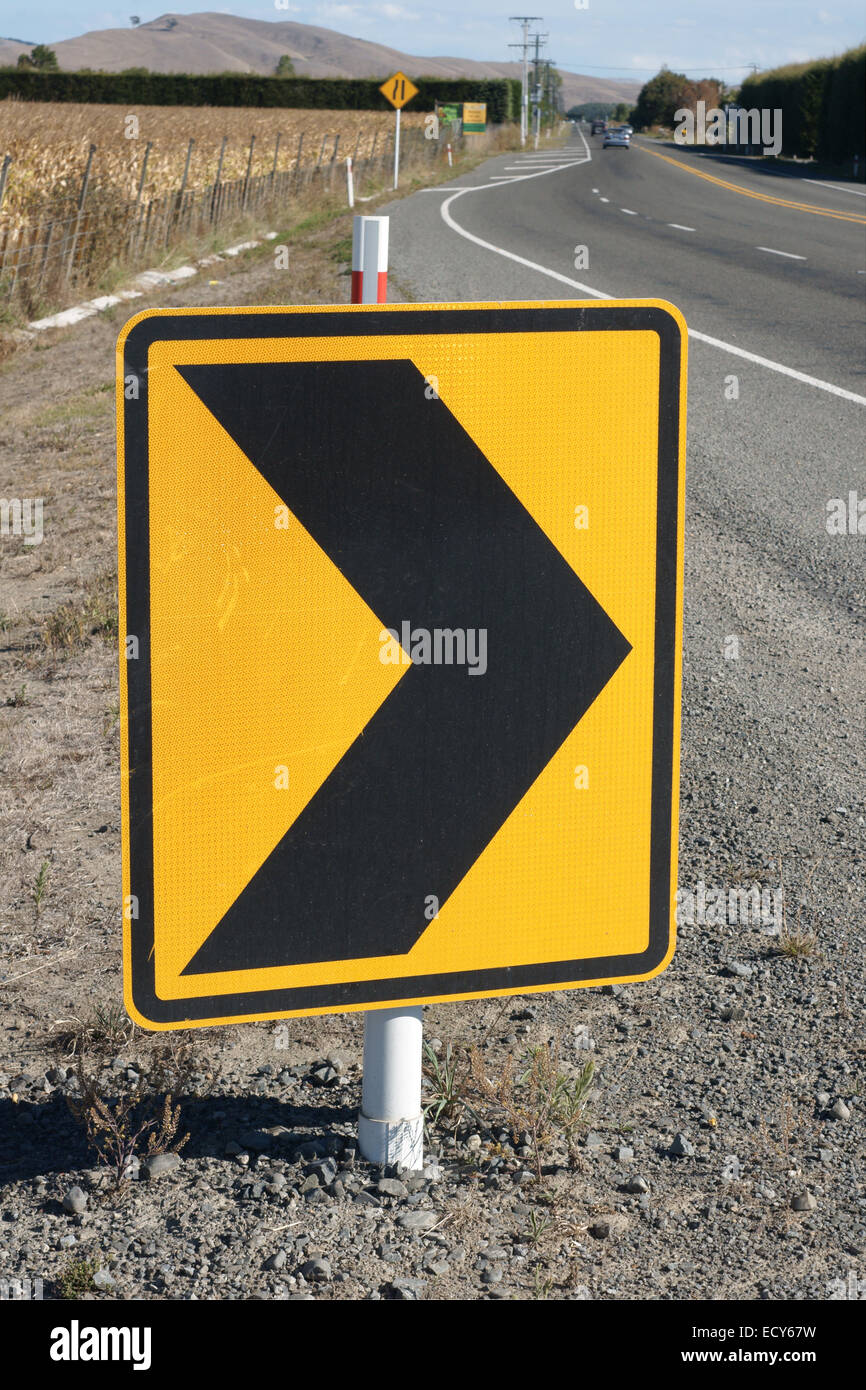 Warning safety chevrons on a rural New Zealand road indicating a bend in the road Stock Photo