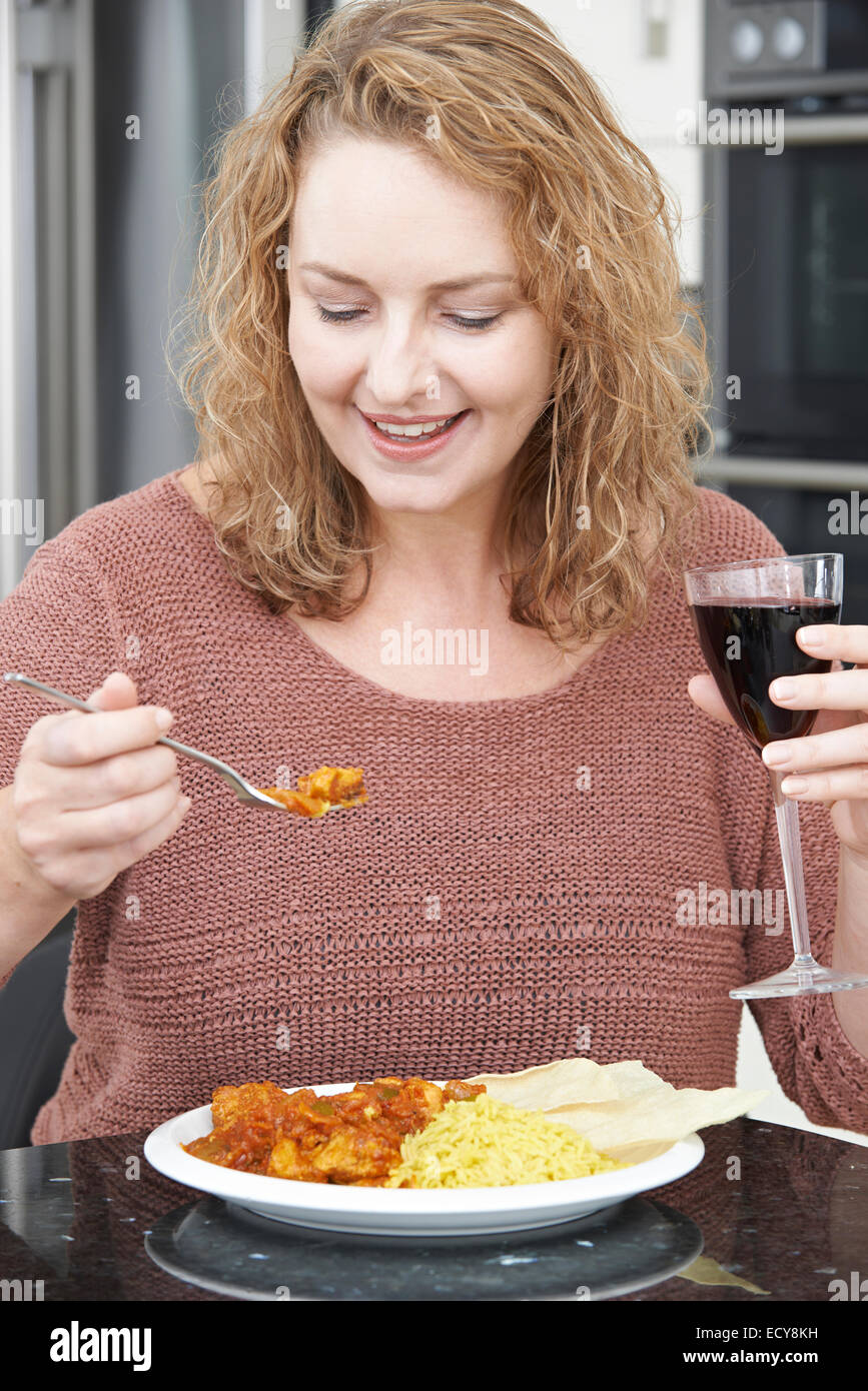 Woman Eating Takeaway Curry And Drinking Wine Stock Photo