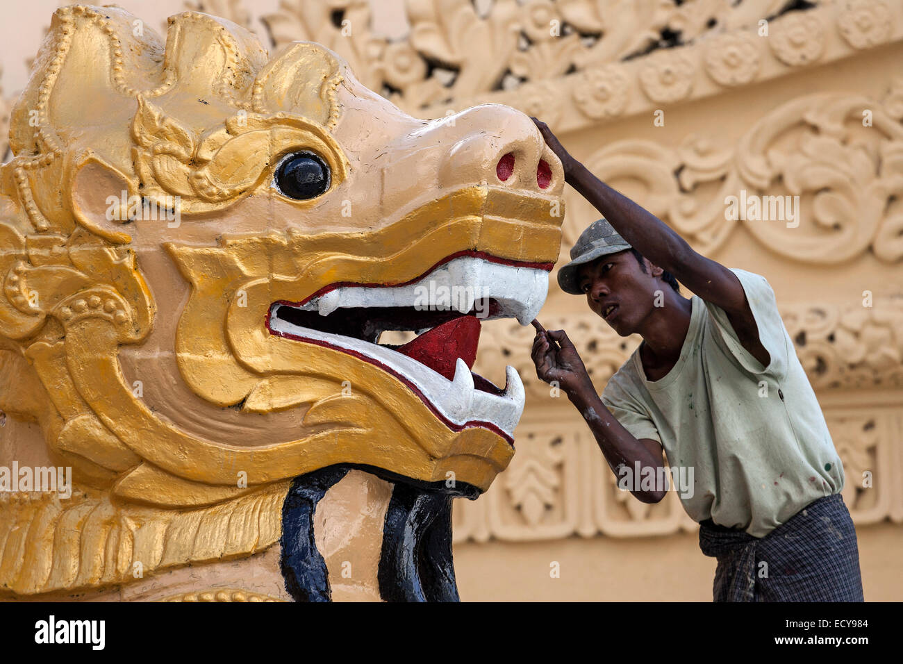 Man carrying out restorations, golden lion's head, Maha Wizaya Pagoda, Yangon, Myanmar Stock Photo