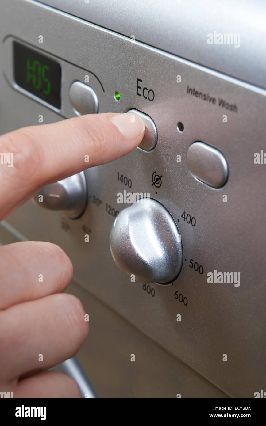 Woman Selecting Economy Program On Washing Machine To Save Energy Stock