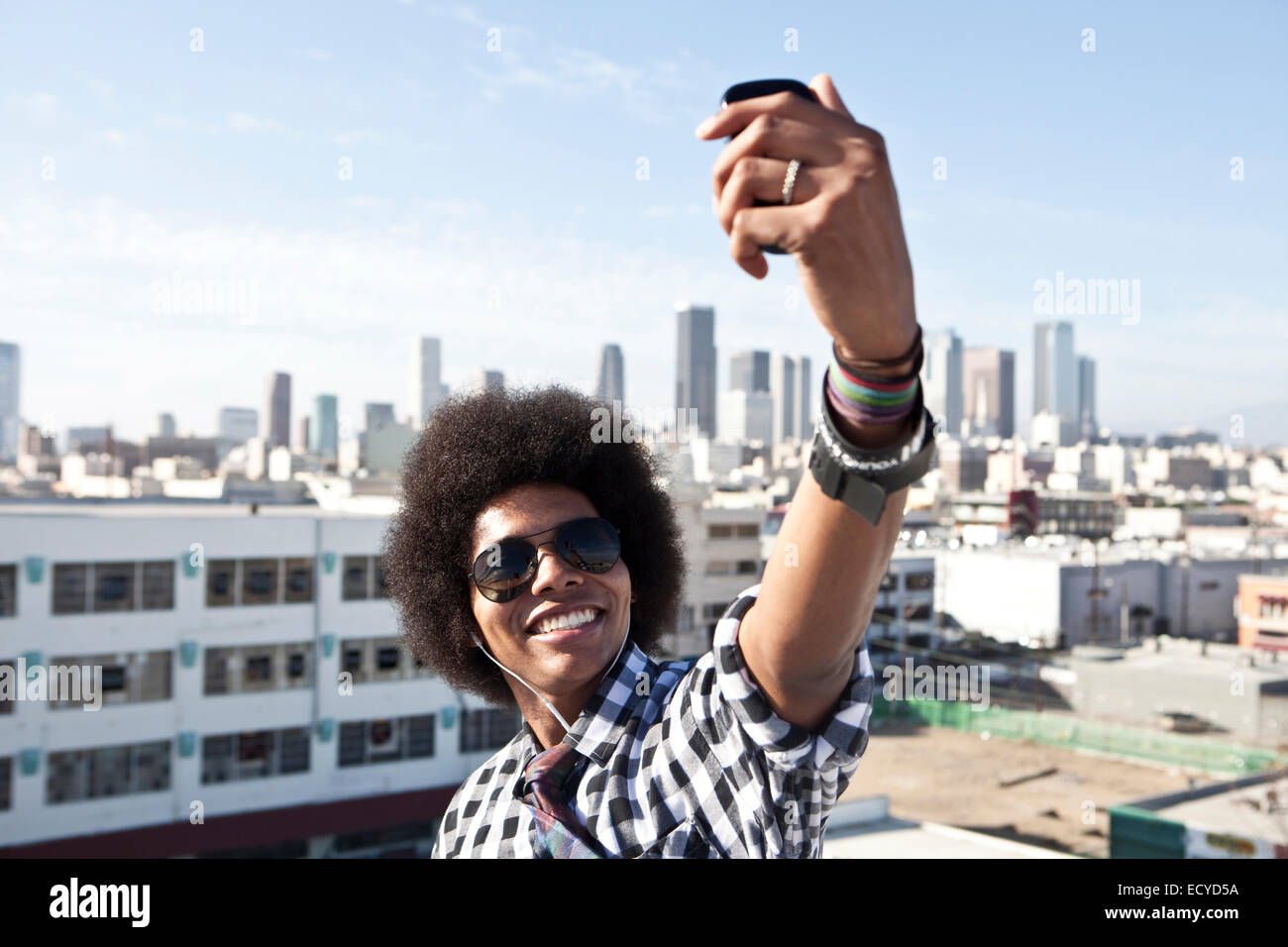 African American man taking cell phone picture from urban rooftop Stock Photo