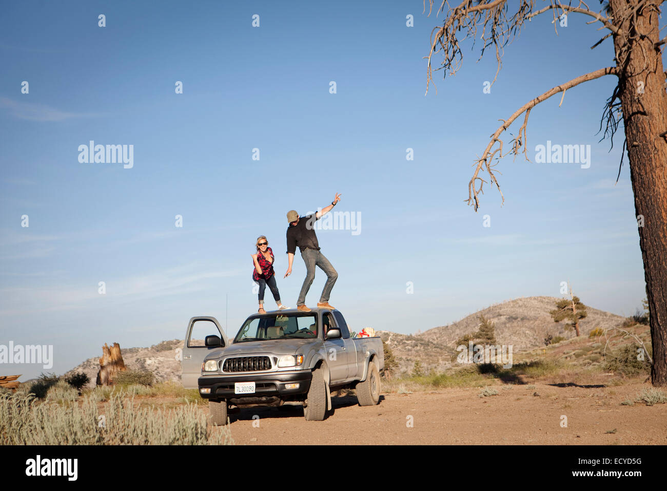 Caucasian couple standing on roof of pickup truck Stock Photo