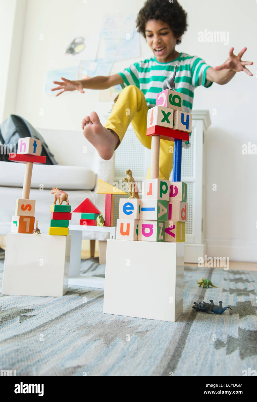 Mixed race boy wrecking wooden block city in living room Stock Photo