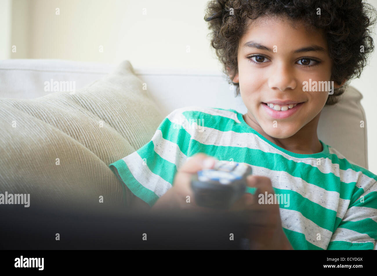 Mixed race boy watching television on sofa Stock Photo