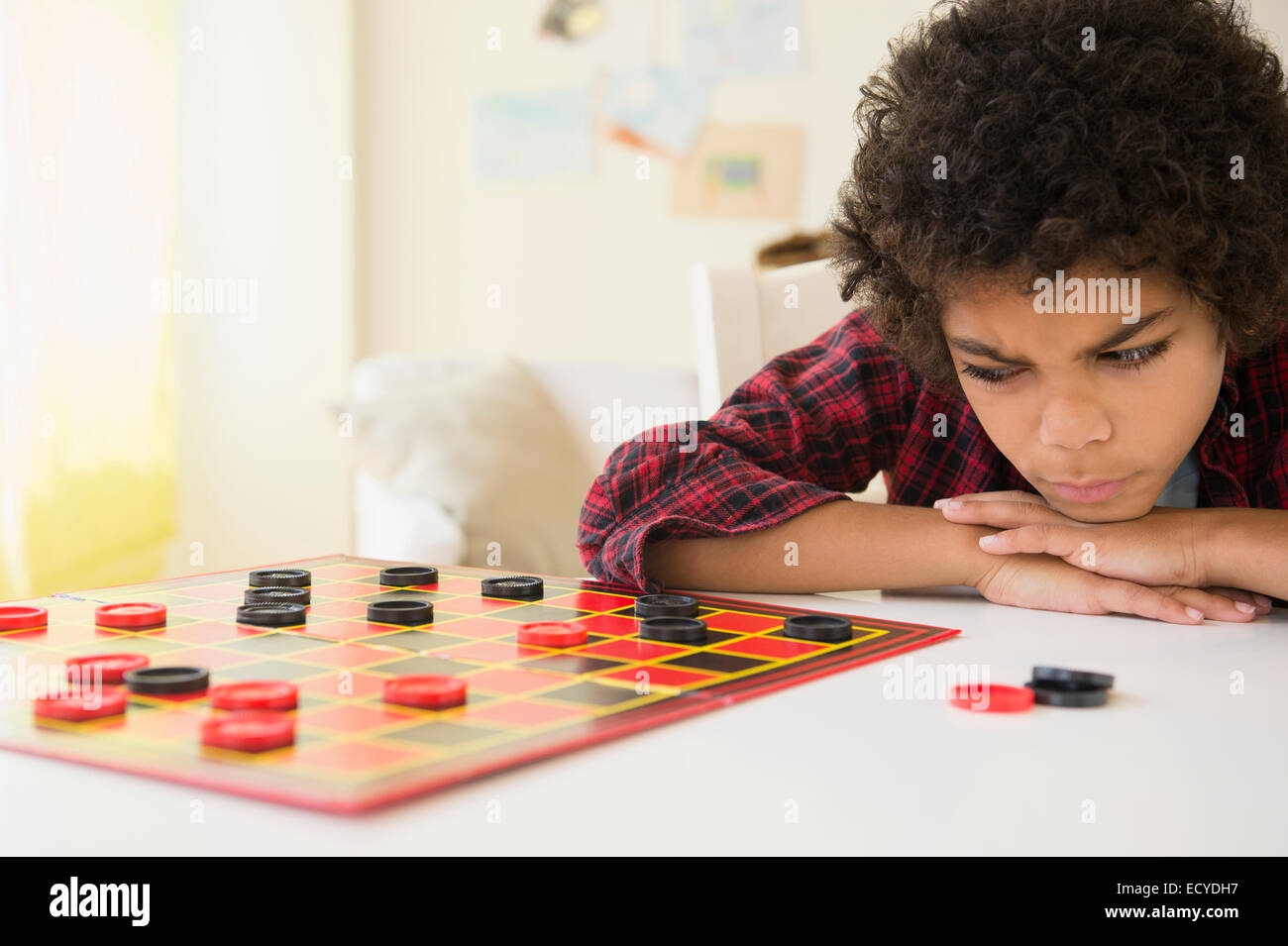 Angry mixed race boy losing game of checkers Stock Photo