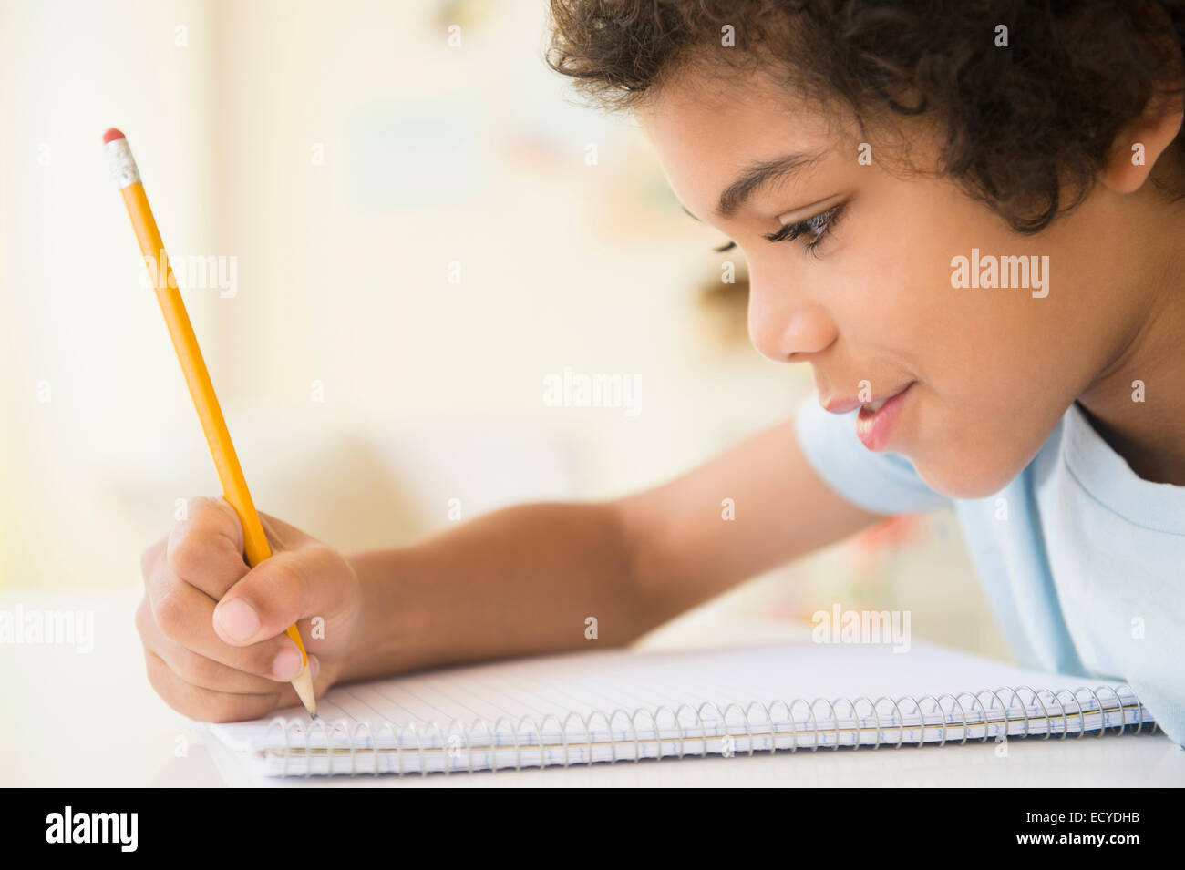 Mixed race boy writing in notebook Stock Photo