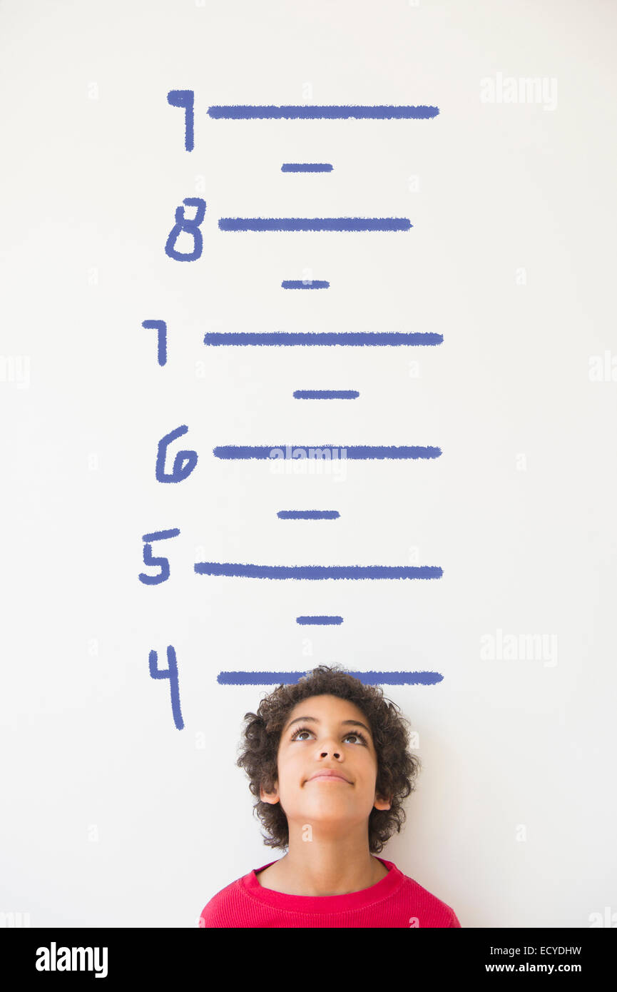 Mixed race boy measuring his height on wall chart Stock Photo