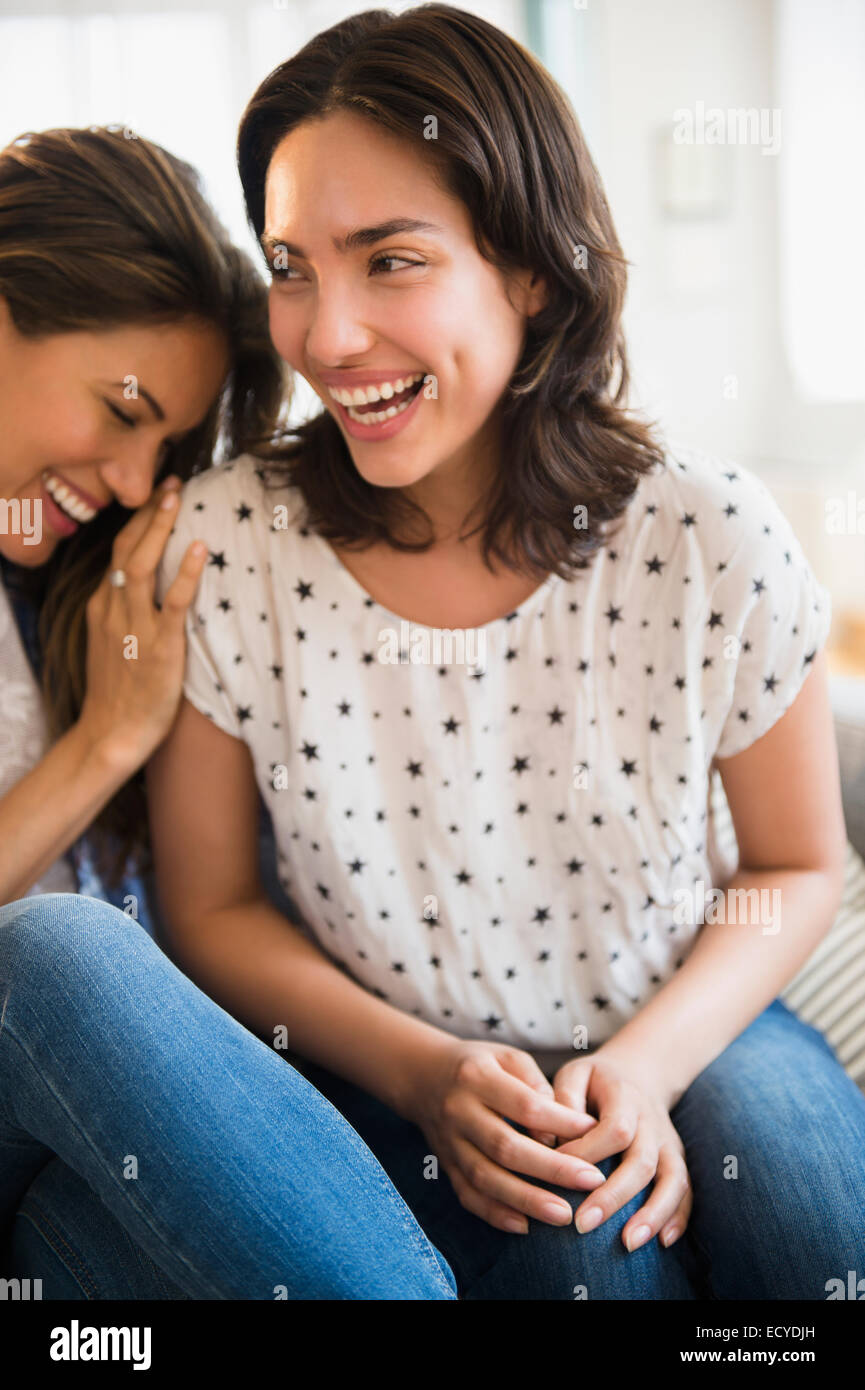 Hispanic women laughing on sofa Stock Photo
