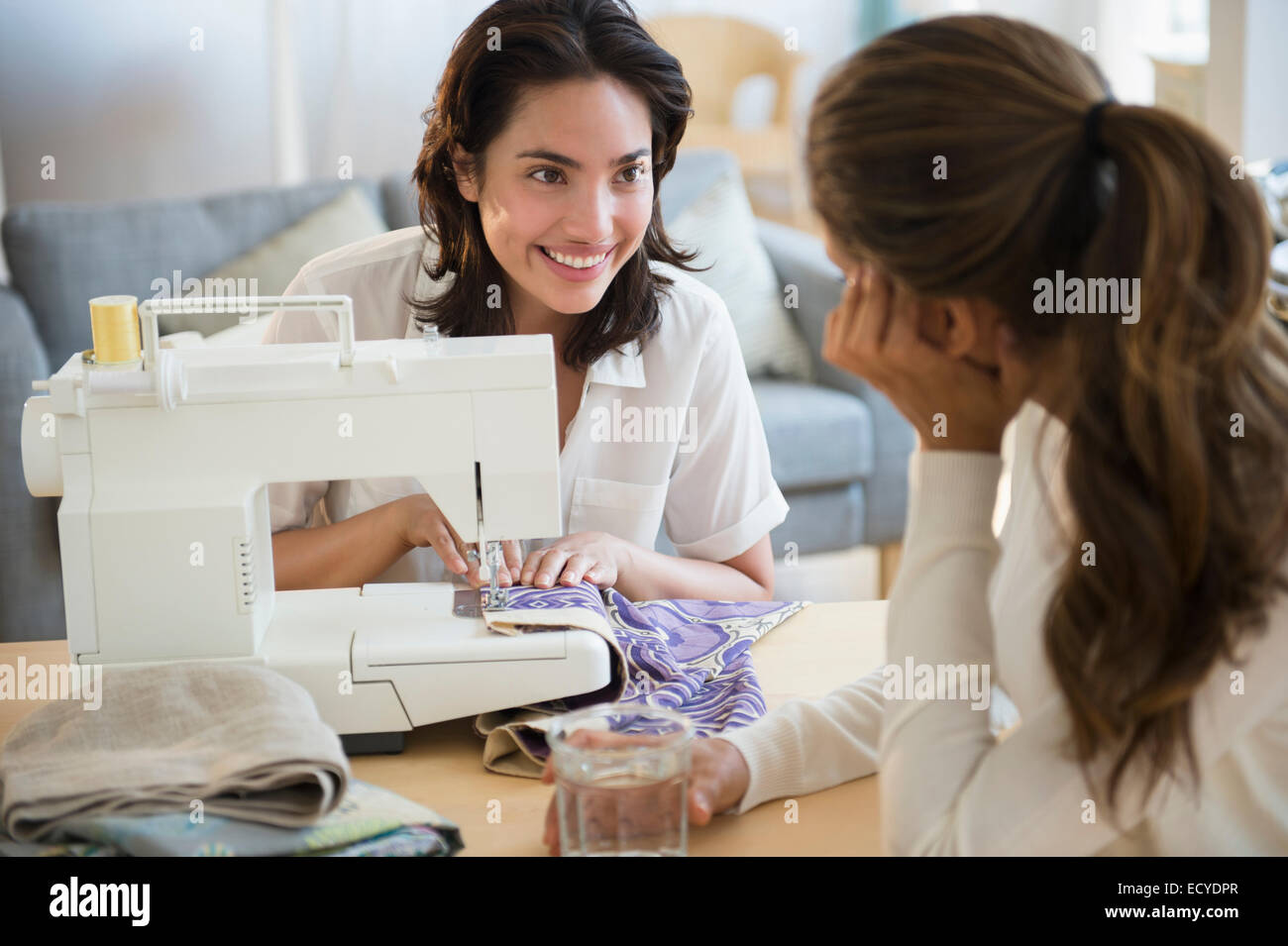 Hispanic women using sewing machine in living room Stock Photo