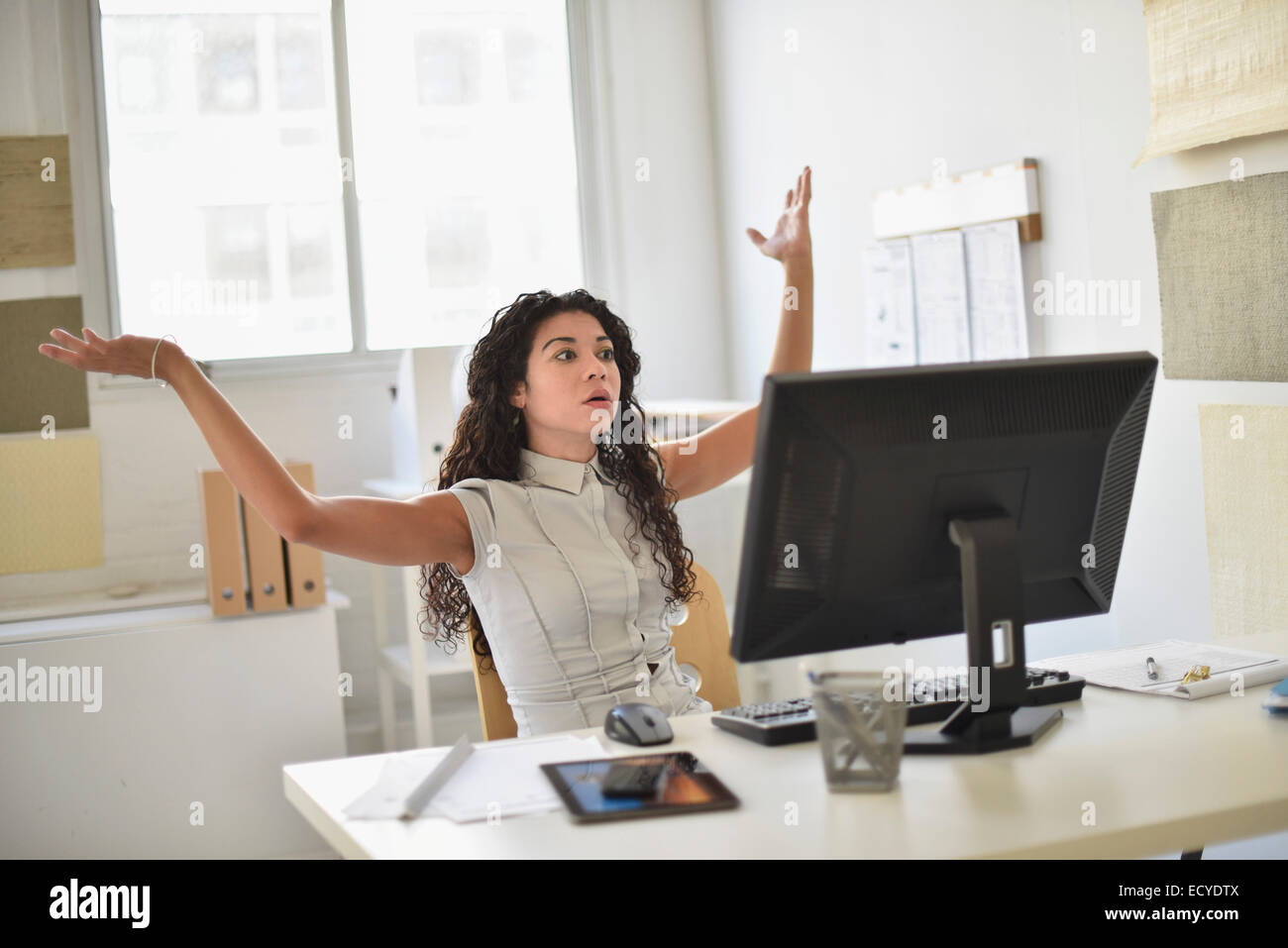 Mixed race businesswoman frustrated at computer at desk in office Stock Photo
