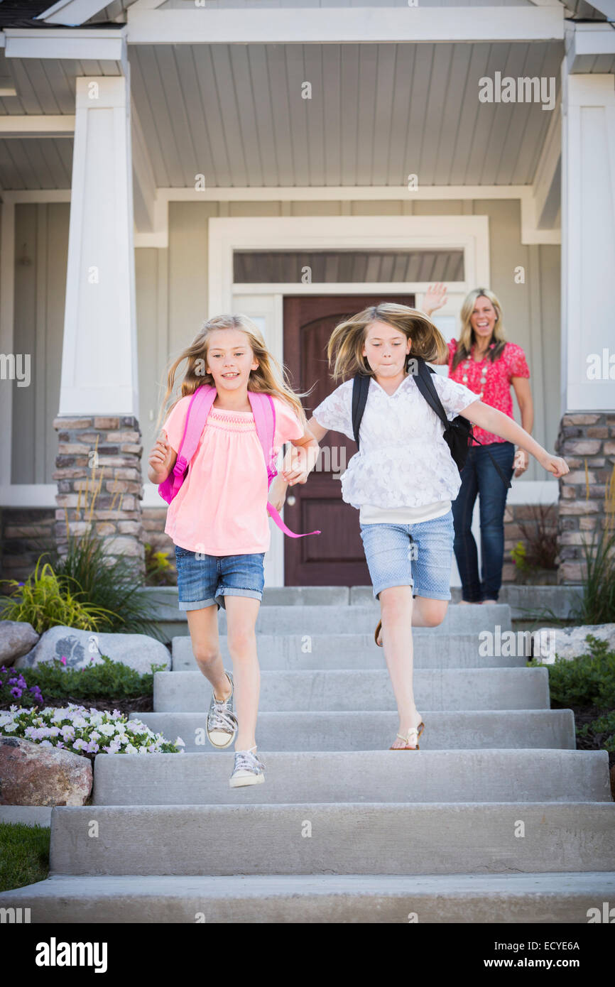Caucasian mother sending running sisters to school Stock Photo