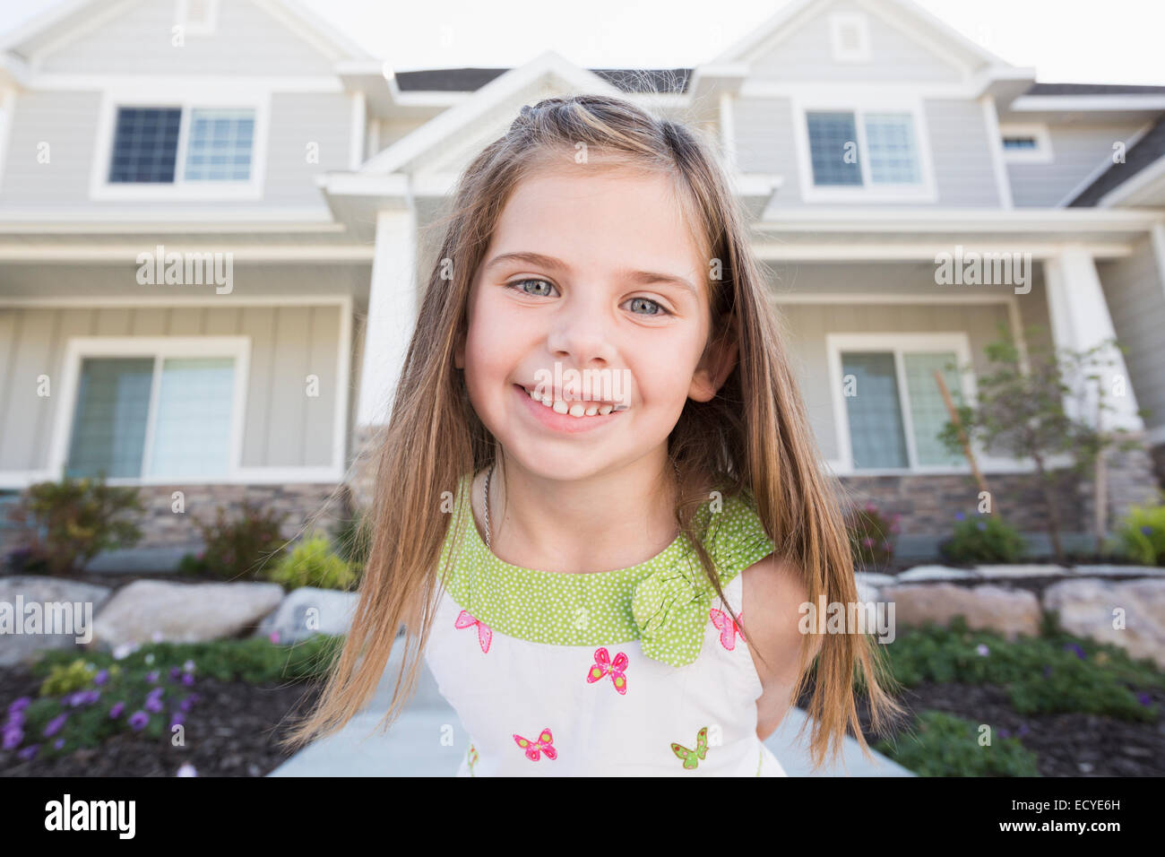 Caucasian girl smiling outside house Stock Photo