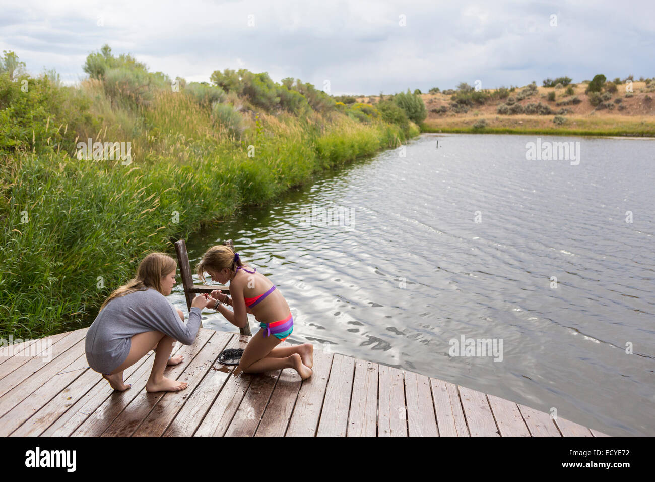 Sisters playing together on wooden dock near lake Stock Photo