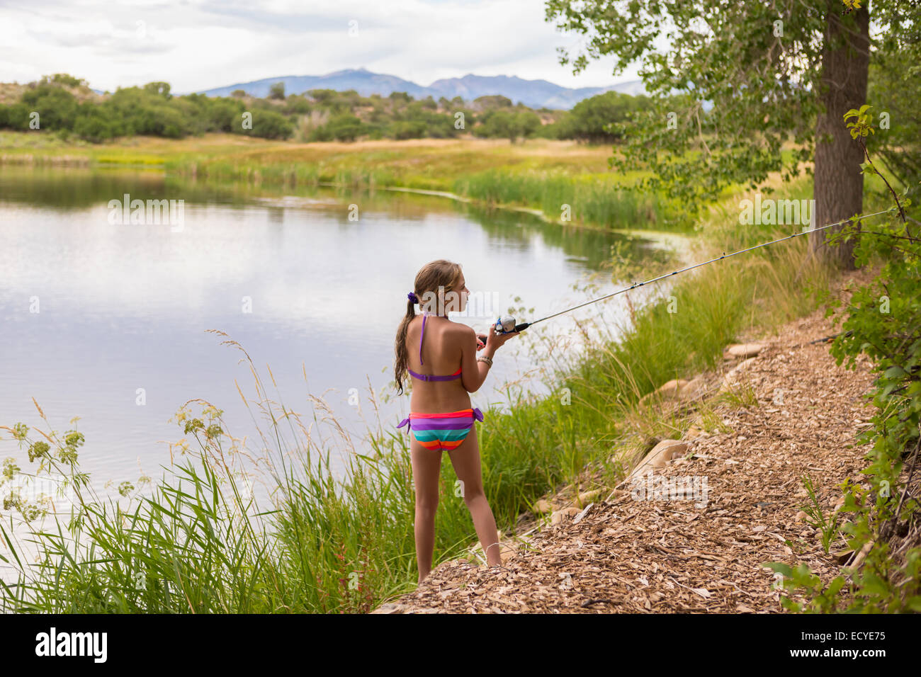 Caucasian girl fishing in rural lake Stock Photo