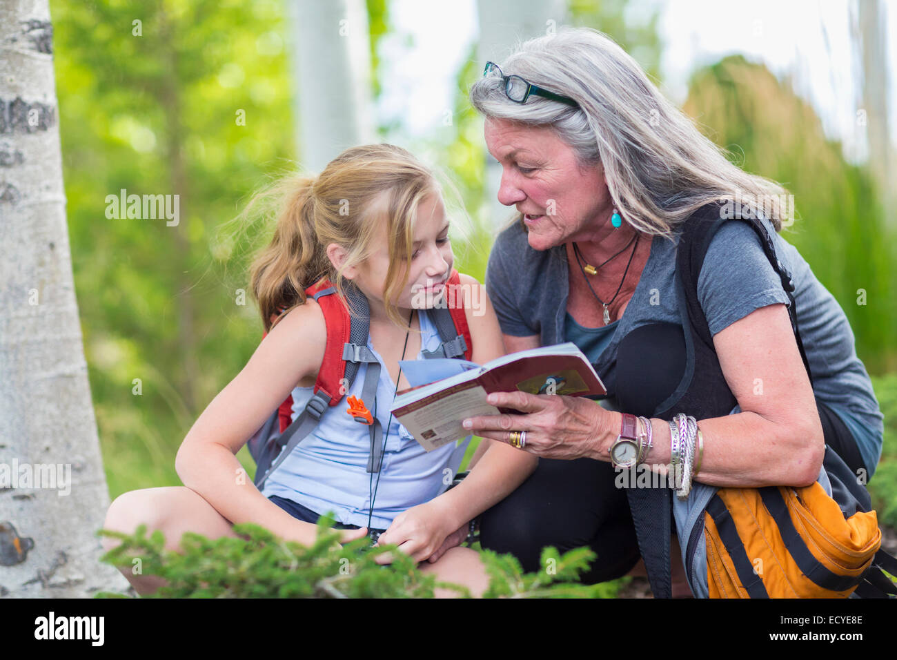 Caucasian grandmother and granddaughter reading guidebook while hiking Stock Photo